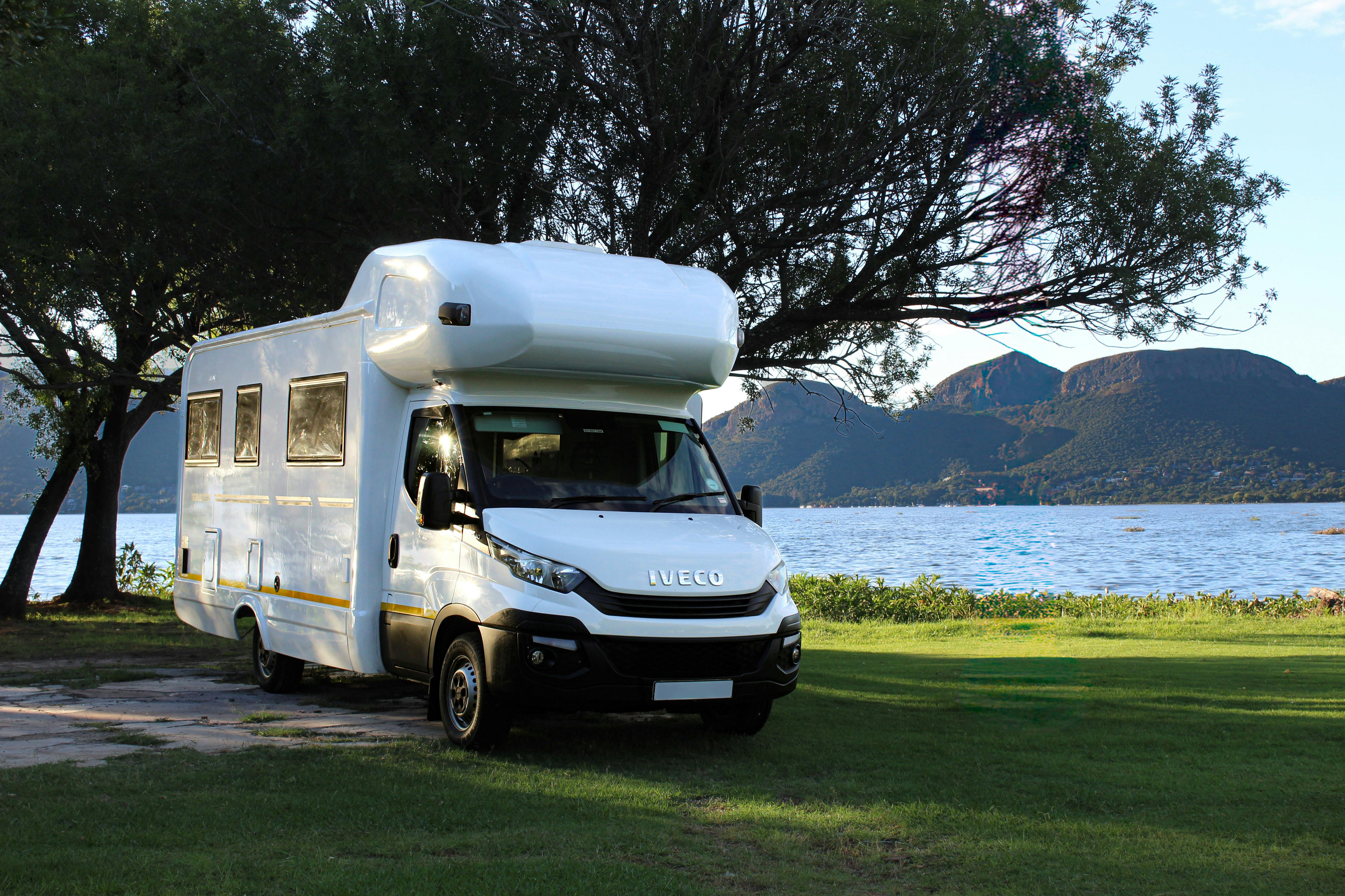 Weißer Alkoven auf Iveco Daily am See mit Bergpanorama